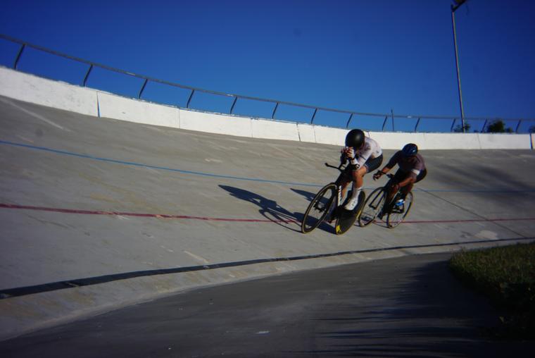 Riders small against a lot of concrete and sky.